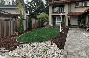 Lush green lawn with landscaped stones and plants by a modern home entrance.