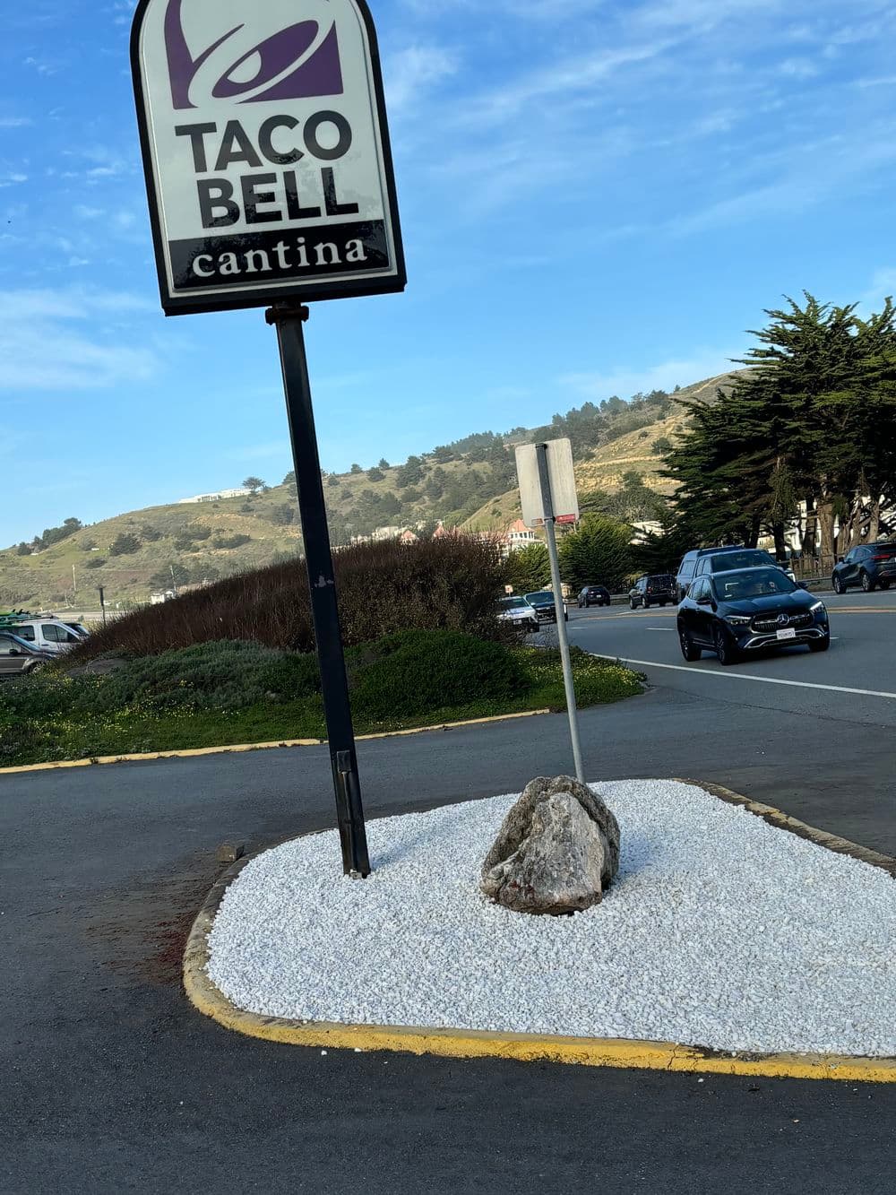 Taco Bell Cantina sign outside with white gravel landscaping and a rock at the entrance.
